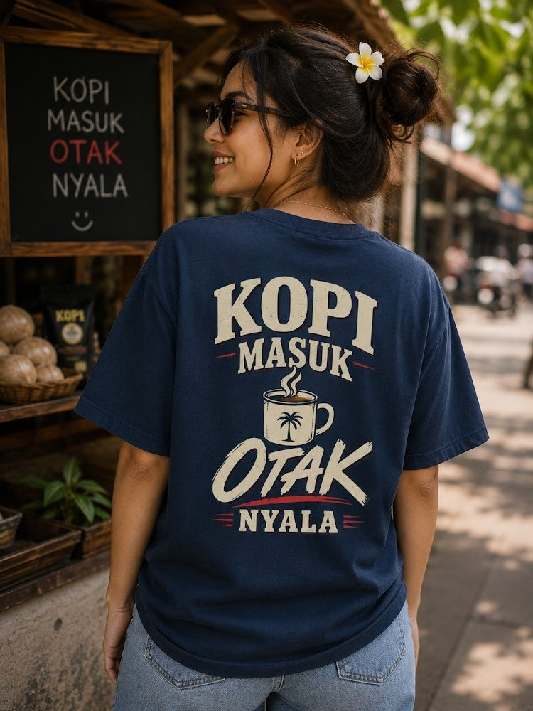 Vrouw draagt JJ Luxury House donkerblauw katoenen T-shirt met Kopi Masuk Otak Nyala print op de rug in buitenomgeving