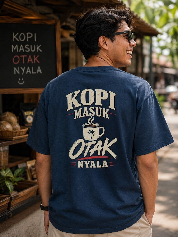 JJ Luxury House donkerblauw katoenen T-shirt met Kopi Masuk Otak Nyala print op de rug, gedragen door een man.